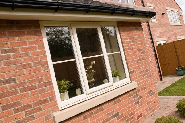 White uPVC casement window installed in red brick house with internal plants on windowsill